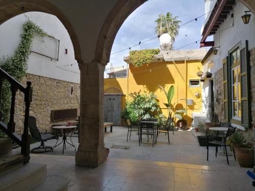 een patio met tafels en stoelen en een gebouw bij Le Mat Hostel in Larnaka