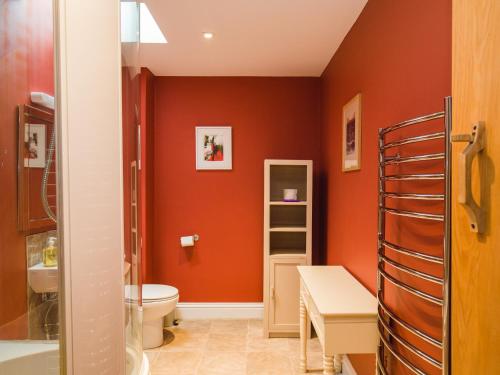 uma casa de banho com paredes cor-de-laranja, um WC e um lavatório. em Tom's Barn em Cheltenham