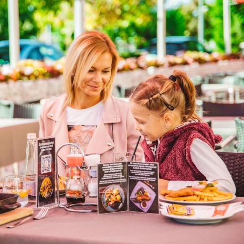 a woman and a little girl sitting at a table at Hotel Paprika in Hegyeshalom