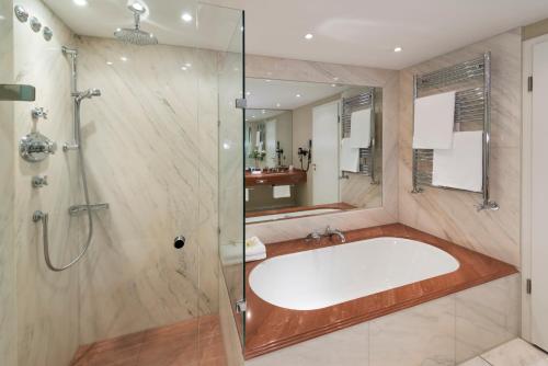 a bathroom with a large tub and a shower at Parkhotel Bremen – ein Mitglied der Hommage Luxury Hotels Collection in Bremen