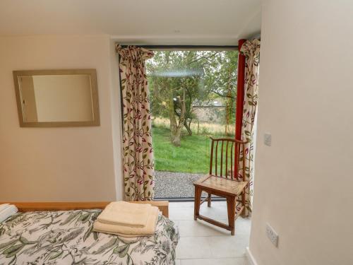 a bedroom with a bed and a chair and a window at Brackenber House in Hilton