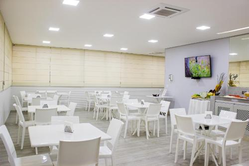 a dining room with white tables and white chairs at Imperial Plaza Hotel in Taguatinga