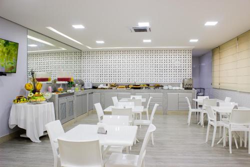 a restaurant with white tables and white chairs at Imperial Plaza Hotel in Taguatinga