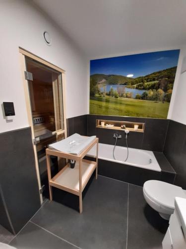a bathroom with a tub and a toilet and a painting at Ferienhaus Familienjuwel am Diemelsee in Diemelsee