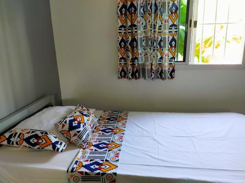 a bed with two pillows on it with a window at Oasis club in Cap Skirring