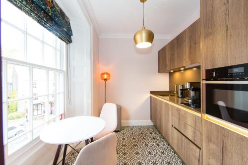 a kitchen with a white table and a white stool at Skeldale House 'All Creatures Great & Small' Luxury Apartments & Studios in Askrigg, Yorkshire Dales in Askrigg