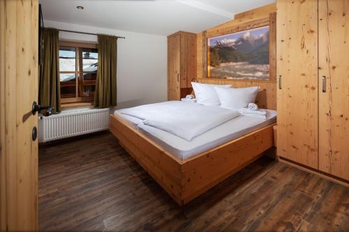 une chambre avec un grand lit en bois avec une fenêtre dans l'établissement Alpenpension Ettlerlehen Ferienwohnungen, à Ramsau bei Berchtesgaden