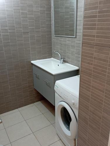 ein Badezimmer mit einer Waschmaschine und einem Waschbecken in der Unterkunft Casa de Yair in Be’er Scheva