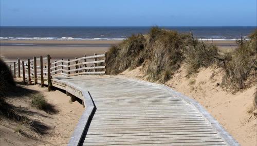 a wooden boardwalk leading to a sandy beach at Formby Guest House in Formby