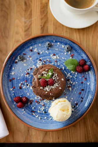 a blue plate with a chocolate muffin and berries at Skrunda Manor in Skrunda