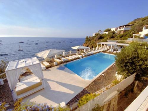 piscina con sedie a sdraio e oceano di La Piazza Luxury Hotel & Spa a Panarea