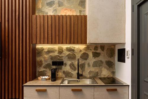 a kitchen with a sink and a stone wall at Bocca al Lupo Villas in Kato Loutraki