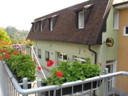 a building with red flowers on a balcony at Pension Zlata Noha in Bratislava
