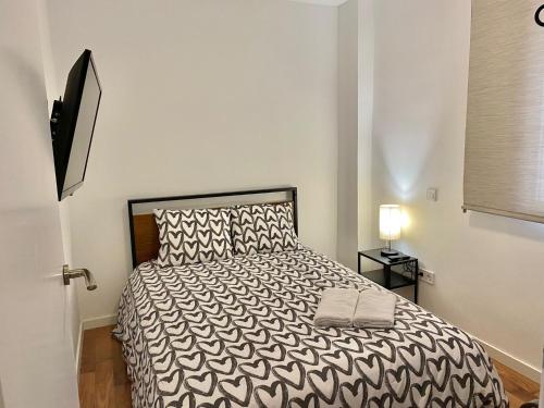 1 dormitorio con 1 cama con edredón blanco y negro en Centro Metro Usera 01, en Madrid