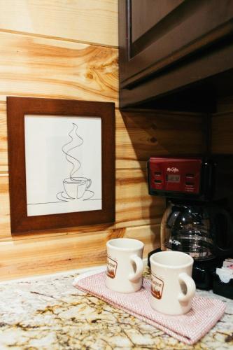 two coffee cups sitting on a counter next to a picture at Fishers of Zen - Broken Bow Vacation Cabin in Broken Bow