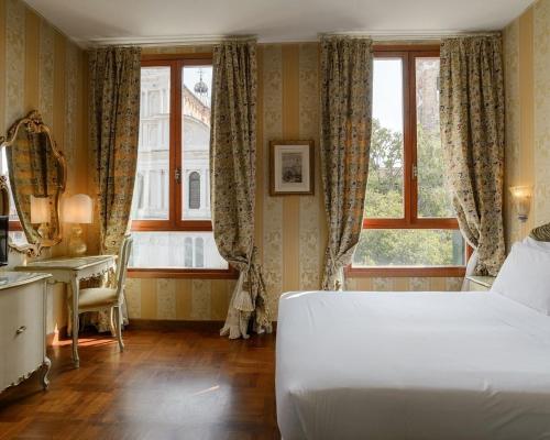 a bedroom with a bed and a desk and a window at Hotel San Zaccaria in Venice