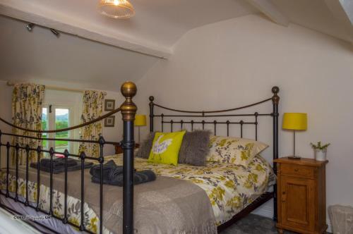 a bedroom with a black bed with yellow pillows at Red Robin Cottage in Gaerwen