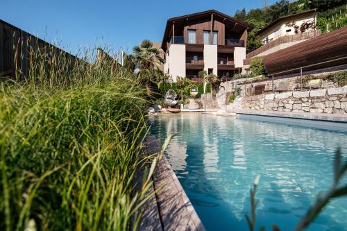 a swimming pool in front of a building at Weingut & Genusshotel Spitalerhof Superior in Chiusa