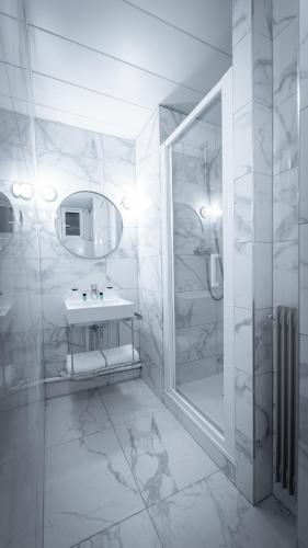 une salle de bain blanche avec un lavabo et une douche dans l'établissement Hôtel du Parc Montparnasse, à Paris