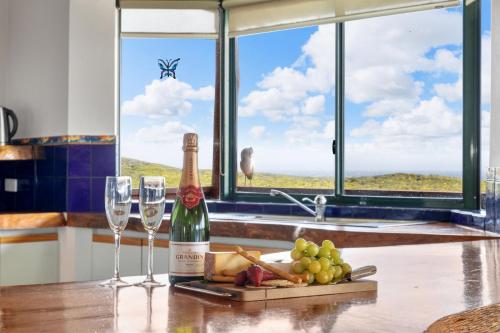a bottle of wine and glasses on a table with a window at Red Door - Enjoy Exclusive Front Row Sunsets from the Balcony & Walks to the Surf in Gnarabup in Gnarabup