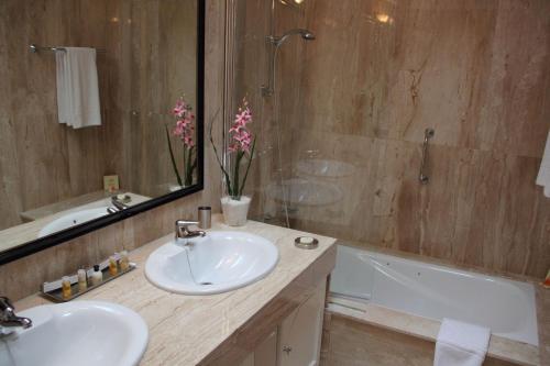 een badkamer met 2 wastafels, een spiegel en een bad bij Villa VIK - Hotel Boutique in Arrecife