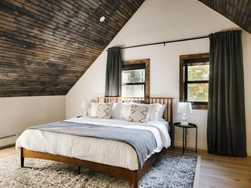 a bedroom with a bed and two windows at Alpine Lodge - Lake Placid, Mirror Lake in Lake Placid