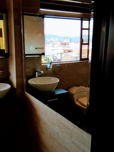 a bathroom with a sink and a toilet and a window at Casa de Huéspedes Tu Parada en Cuenca in Cuenca