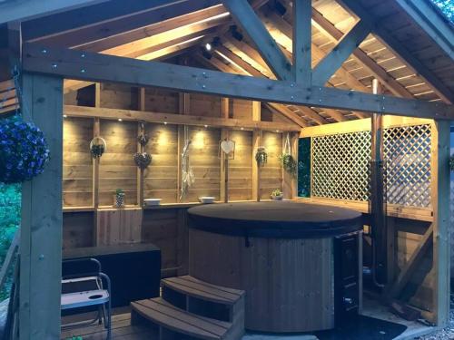 Luxury Log Cabin with Outdoor Wood Fired Hot Tub & Pizza Oven في Ribchester: بروجولا خشبي كبير مع حوض استحمام ساخن