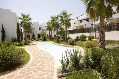 a courtyard with a swimming pool and palm trees at Kaki in San Juan de los Terreros
