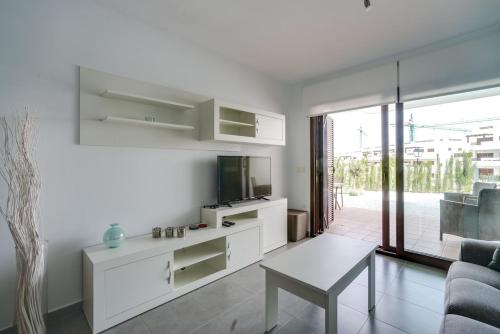 a white living room with a tv and a table at Apartment Chendula in San Juan de los Terreros