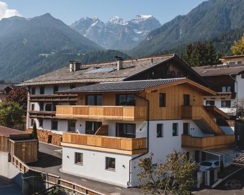 a building with wooden balconies and mountains in the background at Apartment Edith in Telfes im Stubai