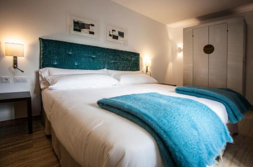 a bedroom with a large bed with a blue blanket on it at Hotel Pura Vida in Valgañón