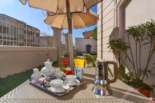 a tray with cups and teapots on a table with an umbrella at Villino Ermione in Marina di Pisa