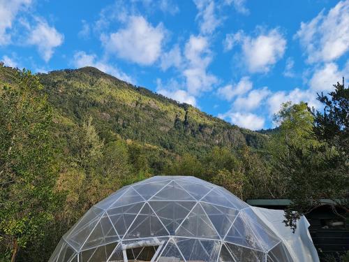 a glass dome with a mountain in the background at Cuyinco Domos in Riñinahue