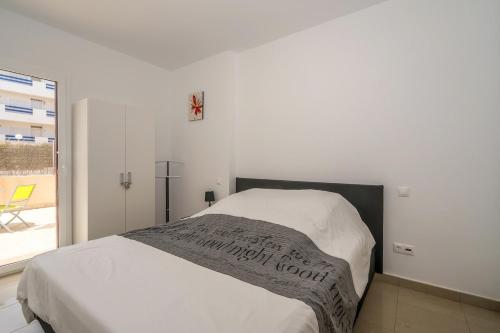 a white bedroom with a bed and a window at El Bosque in Orihuela Costa