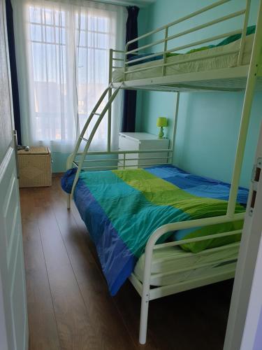 ein Schlafzimmer mit einem Etagenbett mit blauer und grüner Bettwäsche in der Unterkunft Villers sur Mer - Cocon familial, détente, évasion, vue sur mer in Villers-sur-Mer
