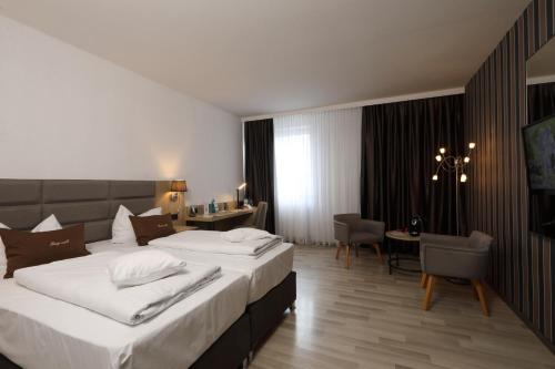 a hotel room with two beds and a desk at Best Western Hotel Rosenau in Bad Nauheim