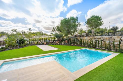 a swimming pool in a yard with a stone wall at Colinas in Orihuela Costa