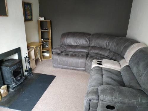a leather couch in a living room with a fireplace at 3-Bed House Sleeps 5 5 min walk from City Centre in Inverness