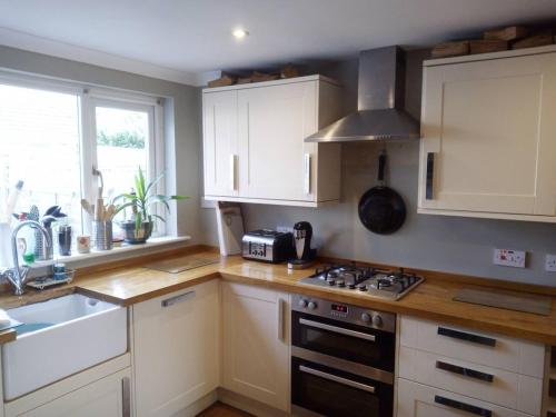 a kitchen with white cabinets and a stove top oven at 3-Bed House Sleeps 5 5 min walk from City Centre in Inverness