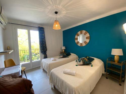 a bedroom with two beds and a blue wall at Hotel Carina in Apt