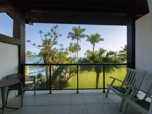 a balcony with a view of the ocean and palm trees at Beach Hotel Maresias in Maresias