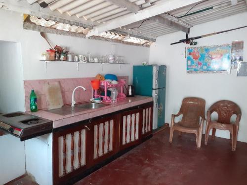 a kitchen with a sink and a refrigerator and chairs at Fort Sea View Hotel in Matara