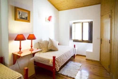 a room with a bed and a table with two lamps at Casas De Romaria in Brotas