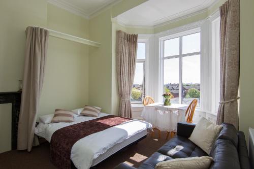 1 dormitorio con cama, sofá y ventana en Glencourt Apartments, en Dublín