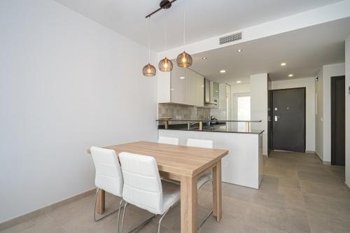 a kitchen and dining room with a wooden table and white chairs at Playa and Chill in San Juan de los Terreros