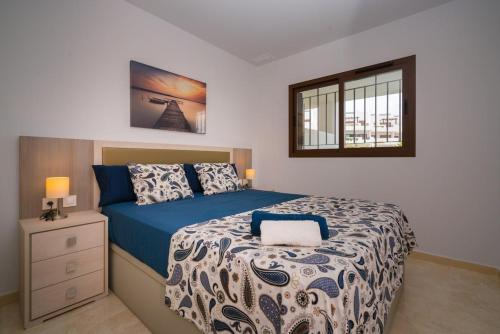 Schlafzimmer mit einem Bett mit einer blauen und weißen Bettdecke in der Unterkunft Apartment Pomelo in San Juan de los Terreros