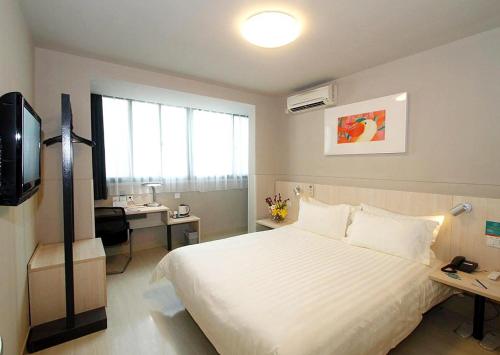 una camera con letto, scrivania e TV di Jinjiang Inn - Economic Development Wujiang a Suzhou