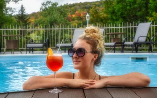une femme dans une piscine avec une boisson dans l'établissement Auberge Hotel Spa Watel, à Sainte-Agathe-des-Monts