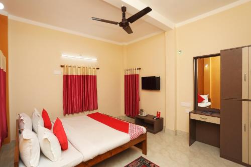 Cette chambre comprend un lit avec des rideaux rouges et une télévision. dans l'établissement Kristi Guest House, Shantiniketan, à Santiniketan